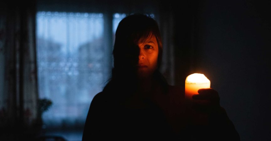 Frau mit Kerze zu Hause wegen Stromausfall