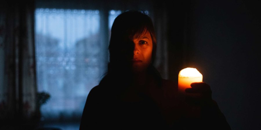 Frau mit Kerze zu Hause wegen Stromausfall