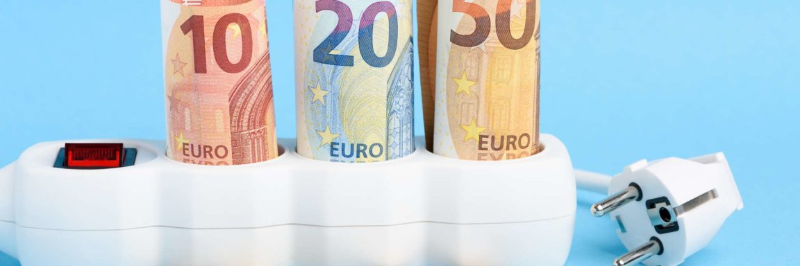 Euro-Scheine in Steckdosenleiste und Stecker mit Münzen auf blauem Hintergrund
