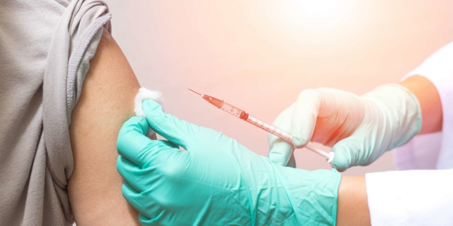 Impfgesundheitskonzept. Hände eines Arztes oder einer Krankenschwester in medizinischen Handschuhen, die einem männlichen Patienten einen Impfstoffschuss injizieren
