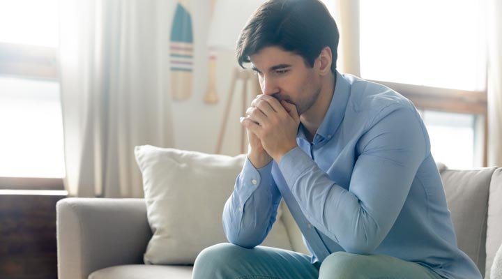 Deprimierter Mann sitzt auf Sofa