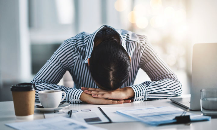 Shot of a young businesswoman lying with her head down on a desk in an office