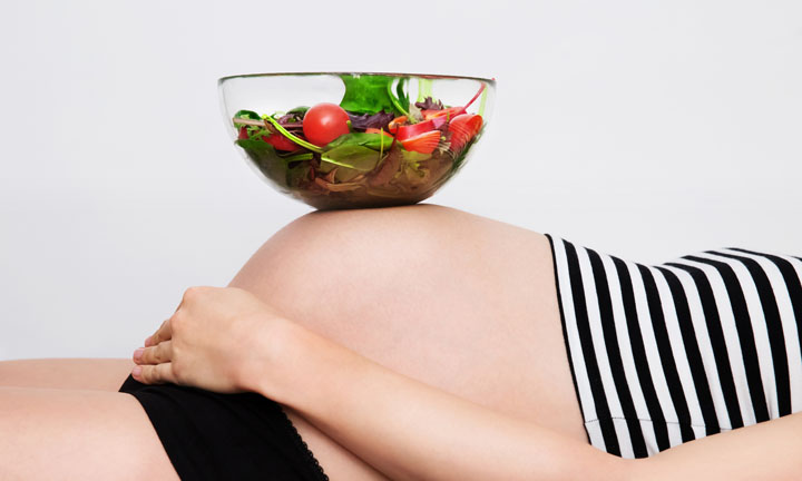 Healthy nutrition and pregnancy. Close-up pregnant woman's belly and vegetable salad