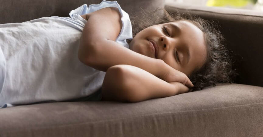 Kleines indisches Mädchen, das zu Hause auf Sofa schläft