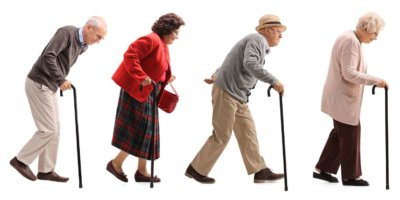Ältere Menschen, die in einer Linie hinter einem älteren Mann mit Warnweste und Stoppschild laufen