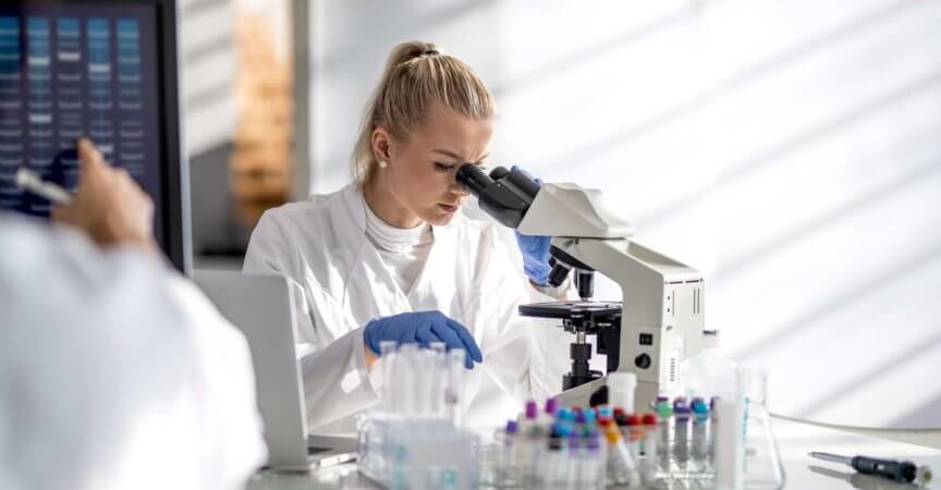 Wissenschaftlerin, die durch ein Mikroskop schaut