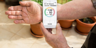 An elderly man measures blood pressure and pulse by mobile phone with medical application