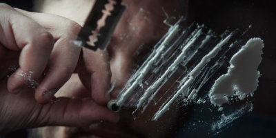 Man snorting cocaine in dark room. Drug addict concept.