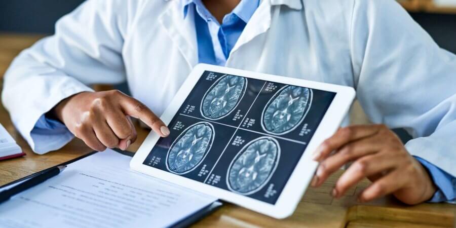 Aufnahme einer Ärztin, die während einer Beratung in ihrer Praxis ein digitales Tablet verwendet, um einen Gehirnscan zu besprechen