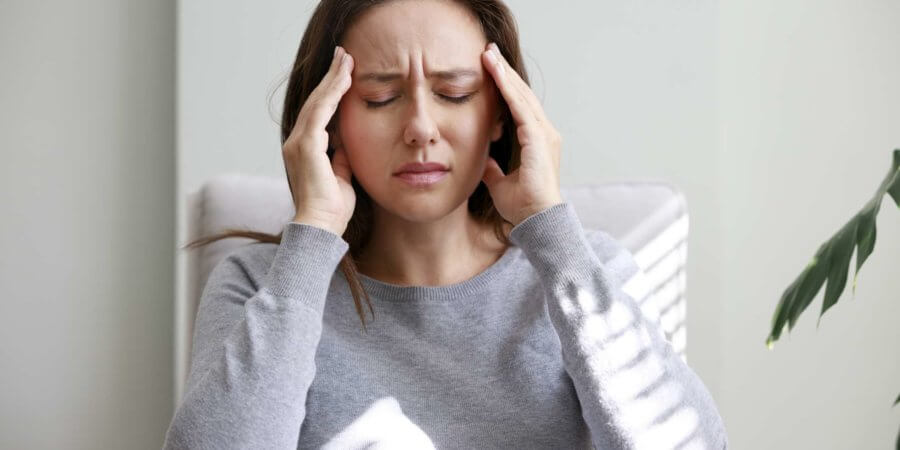 Aufnahme einer jungen Frau, die sich aufgrund von Schmerzen zu Hause den Kopf hält