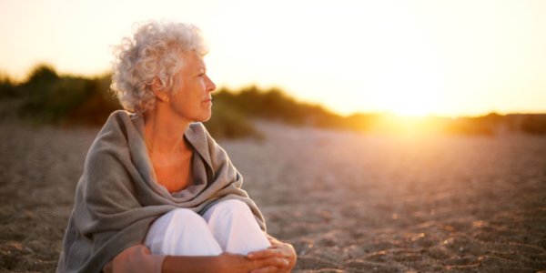 Ältere Dame sitzt am Strand
