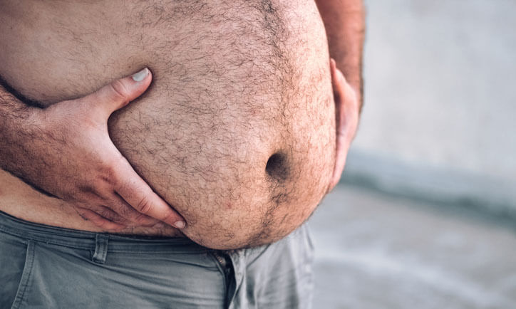 Close-up of a man's round and full hairy belly, with both hands holding it up
