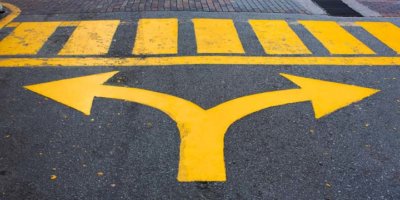 Yellow turn left and turn right arrow sign on asphalt road