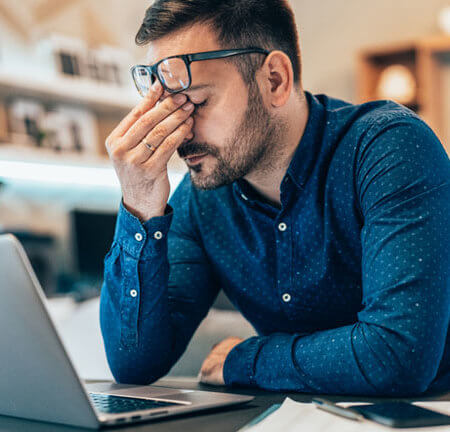 Tired young businessman working at home using lap top and looking Anxious