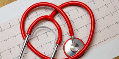 Nahaufnahme des roten Herzstethoskops auf Papier des Elektrokardiogramms (EKG).