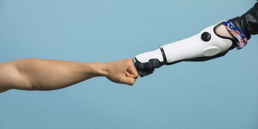Eine menschliche Hand und eine Roboterhand treffen sich in der Mitte und berühren die Knöchel.