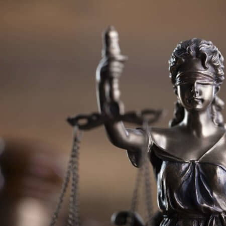 Zusammensetzung von Gesetz- und Gerechtigkeitssymbolen: Richterhammer, Waage und Themis-Skulptur.