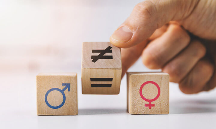 gender equality and discrimination concept - hand putting wooden blocks with symbols