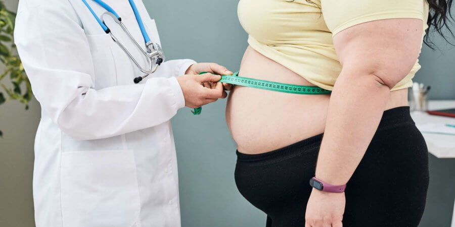 Fettleibigkeit, ungesundes Gewicht. Ernährungsberater untersucht die Taille einer Frau mit einem Messband, um eine Diät zur Gewichtsabnahme zu verschreiben