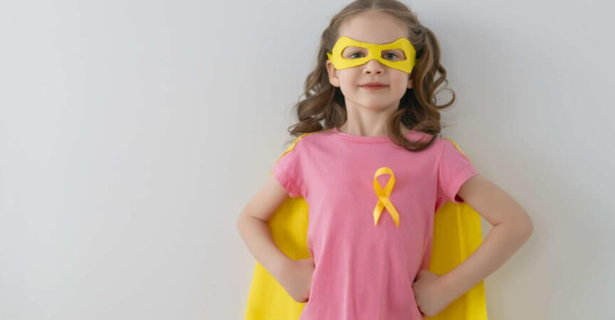 Weltkinderkrebstag. Mädchen im Superheldenkostüm mit goldenem Band.