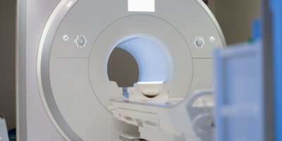 Modern magnetic resonance imaging machine standing in clinic background. New medical technologies concept