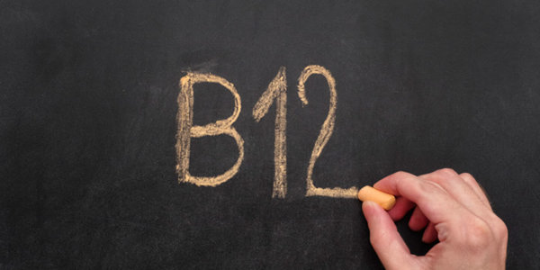 Mann schreibt Wort B12 auf Tafel. Vitamin B12-Konzept. Nahaufnahme.