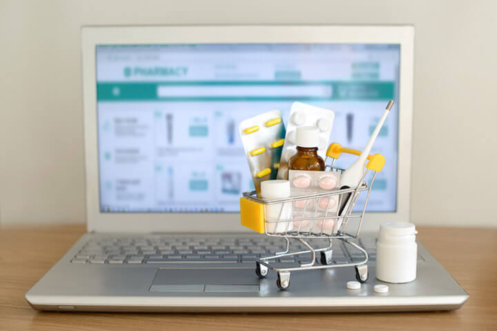 Spielzeug-Einkaufswagen mit Medikamenten auf einem Laptop.
