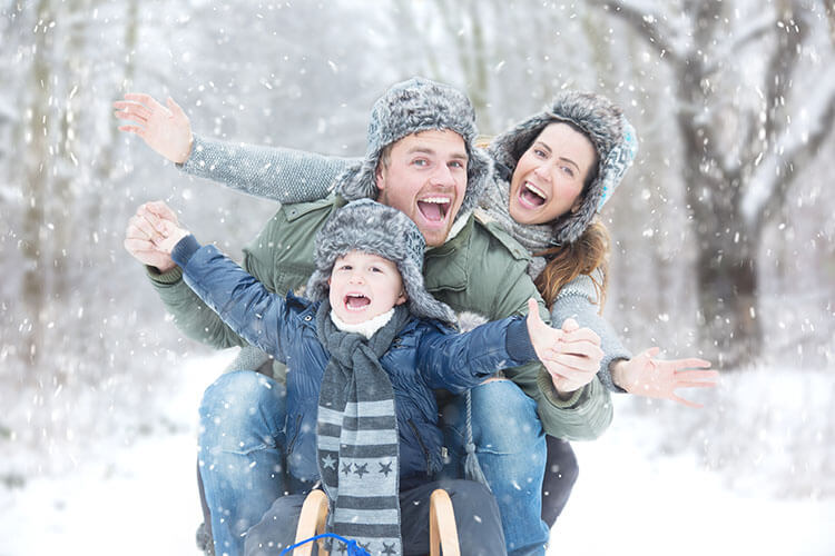 Fröhliche Familie auf Schlitten im Schnee.