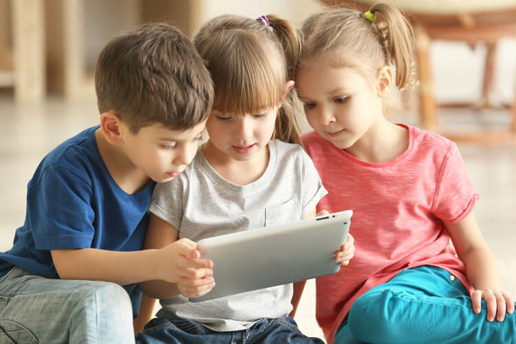 Drei Kinder schauen auf ein Tablet