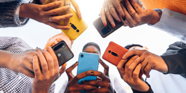 Smartphones in den Händen von Jugendlichen, die im Kreis stehen