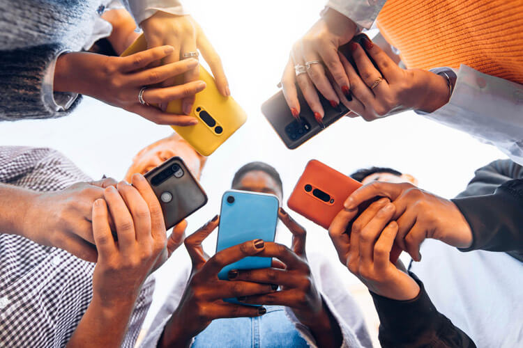 Smartphones in den Händen von Jugendlichen, die im Kreis stehen